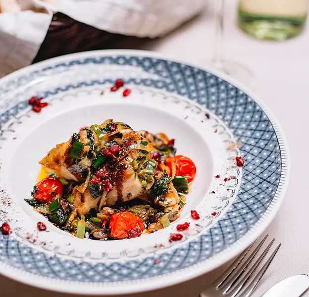 Plat de poisson grillé avec tomates cerises et légumes verts sur une assiette décorée à Chénérailles dans la Creuse 23