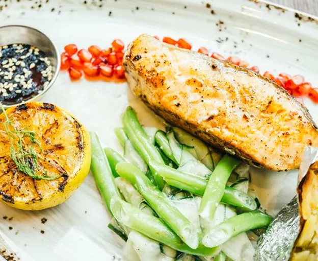 Saumon grillé, citron, haricots verts, grenade et sauce sur assiette blanche à Chénérailles dans la Creuse 23