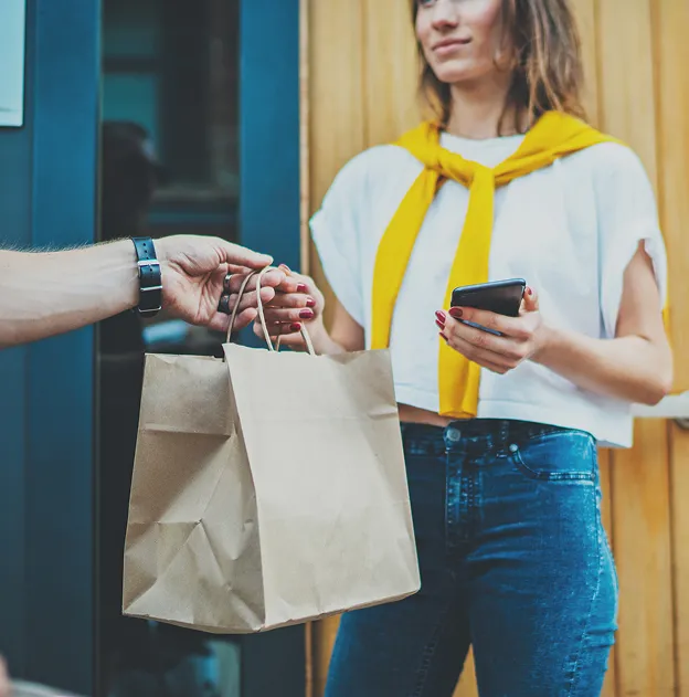 Une femme reçoit un sac de courses d'une personne, tenant un téléphone à Chénérailles dans la Creuse 23